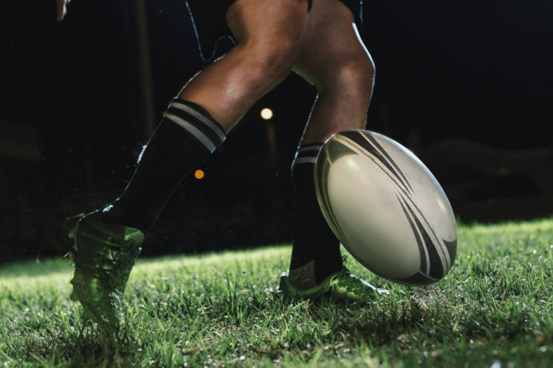A rugby player kicking a ball at night. | FCE Scan